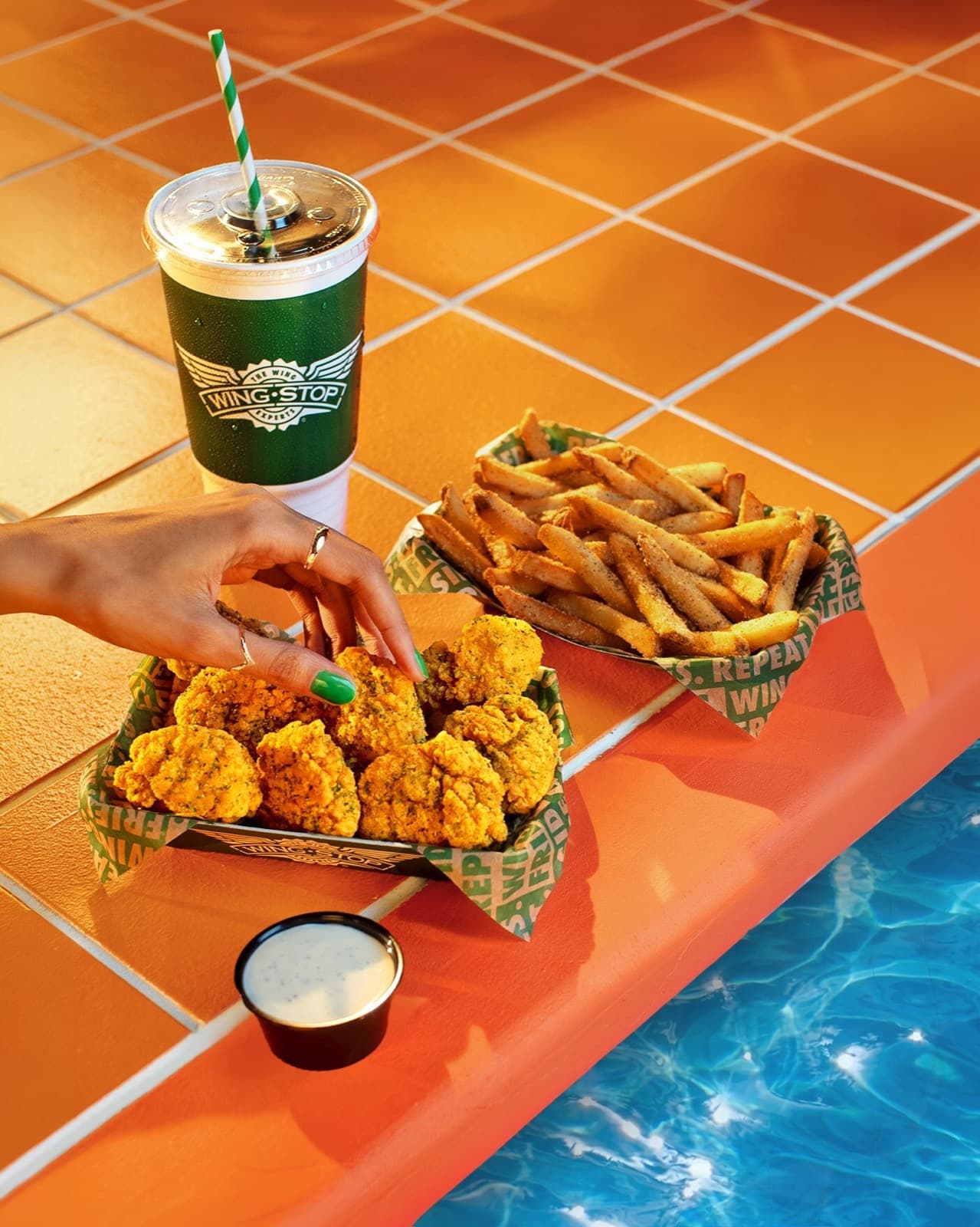Crispy seasoned wings and lemon-pepper fries in green Wingstop boats